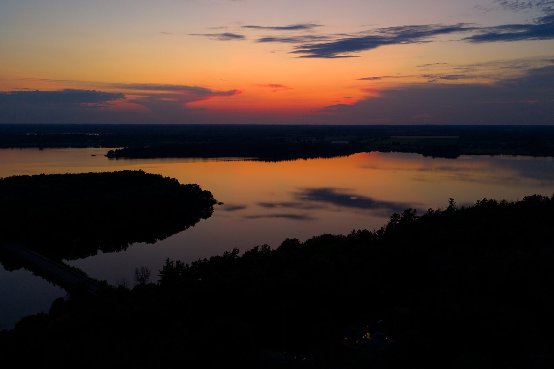 Sunset over a dark lake and tree line