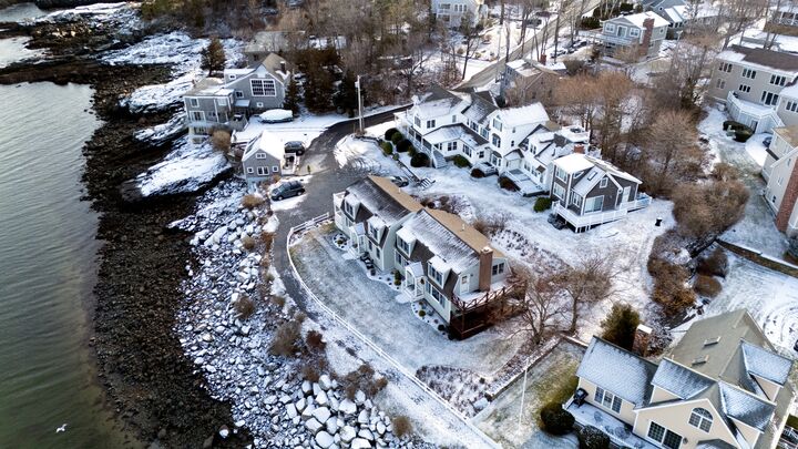 Snow-dusted houses along a rocky shoreline, from above