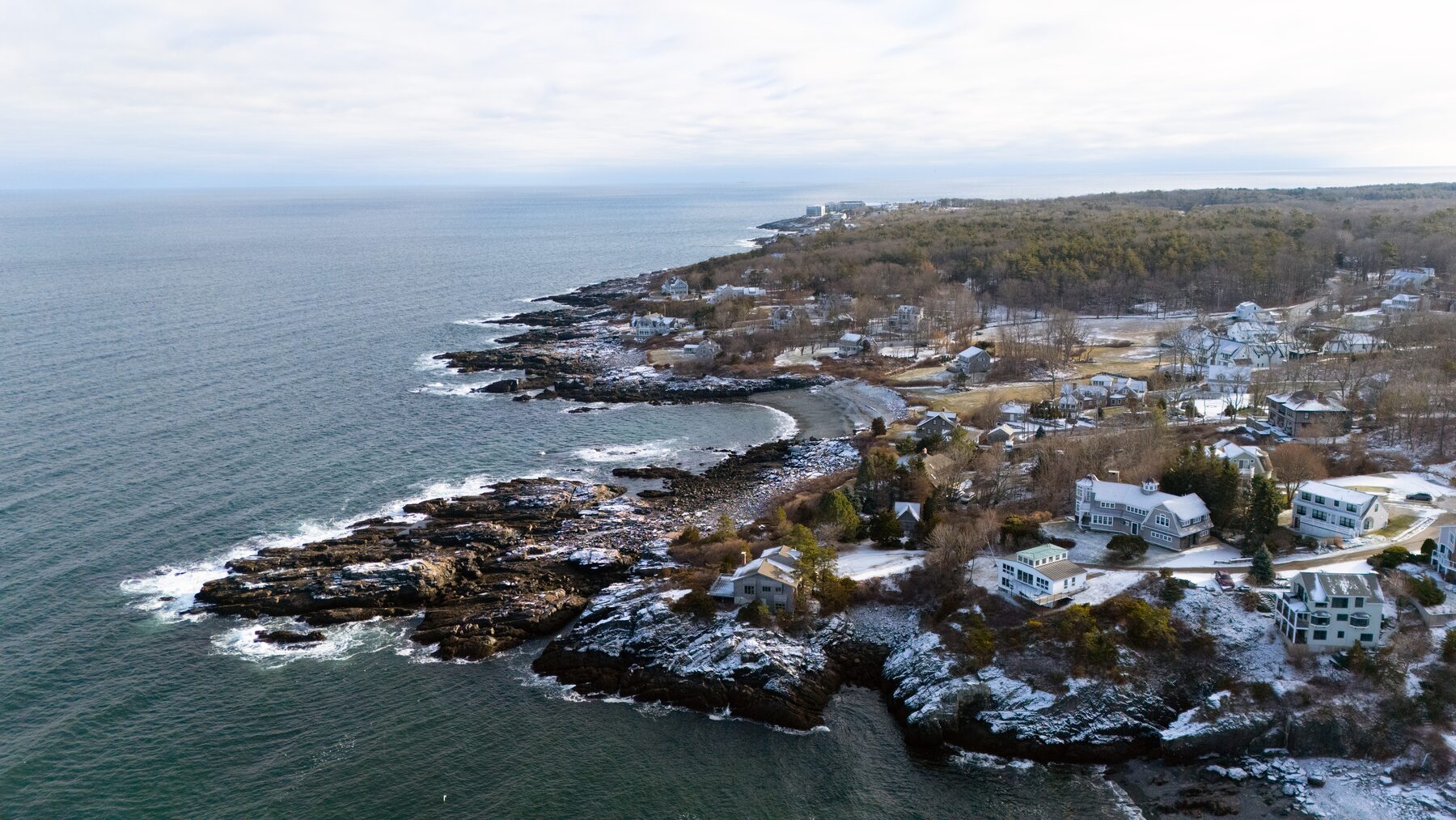 Rocky cove with houses along the shore under a grey sky