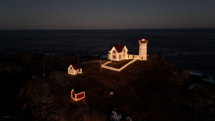 Lighthouse lit up at night on a dark headland