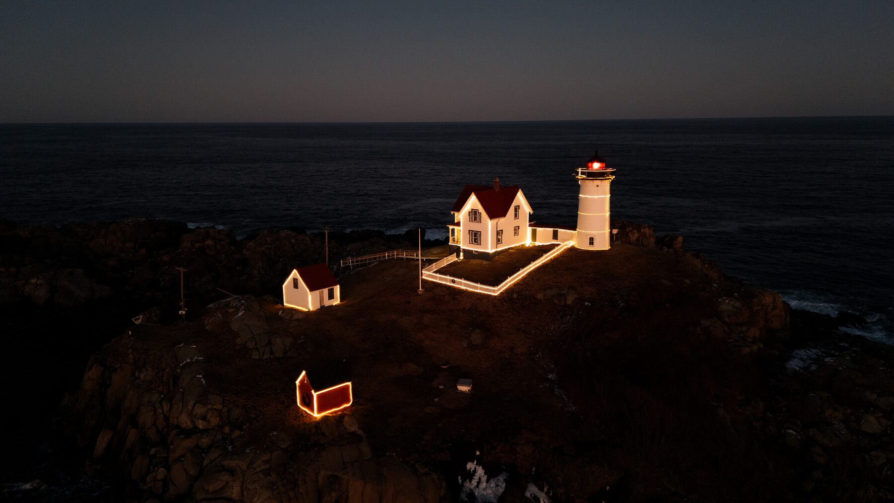 Lighthouse lit up at night on a dark headland